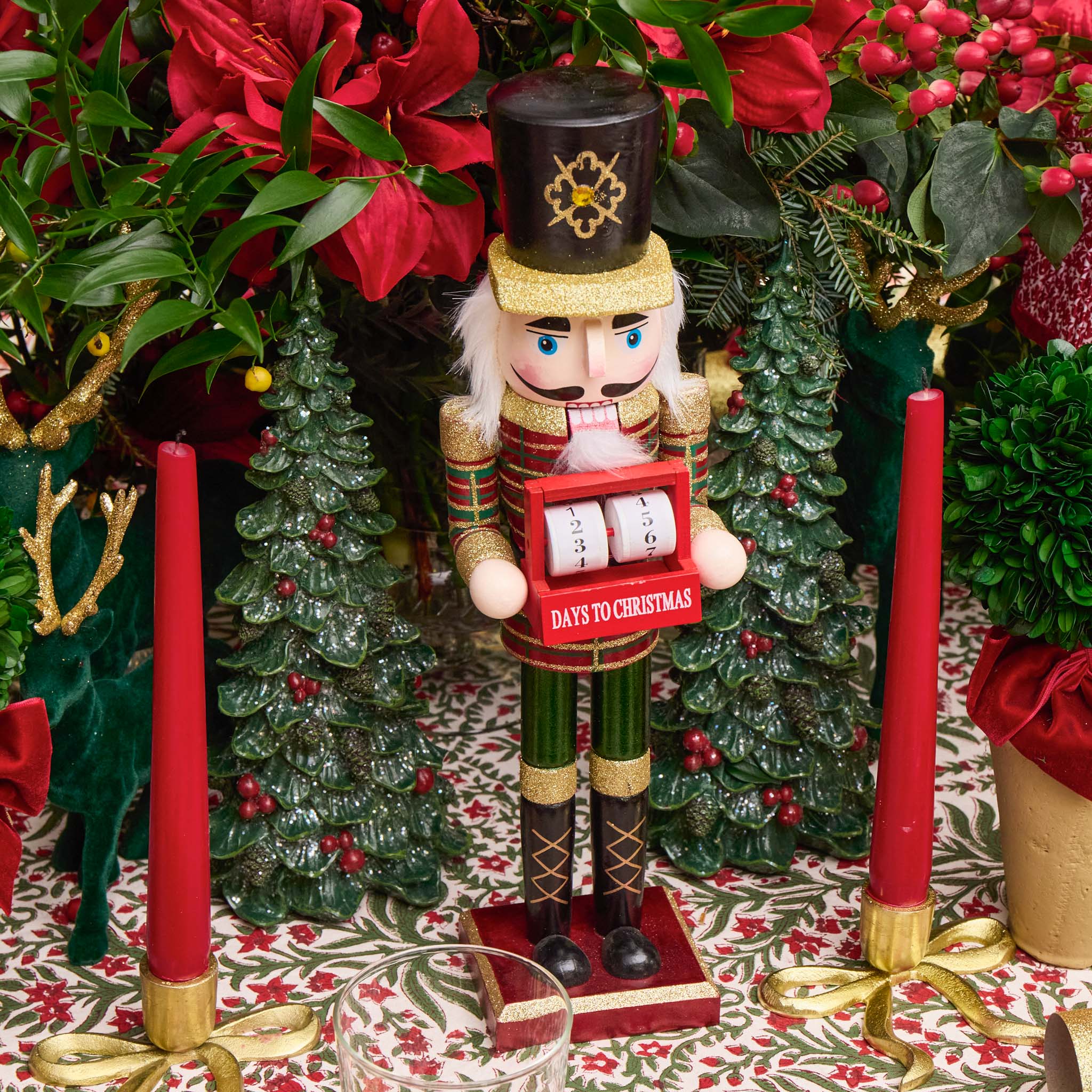 Nutcracker figurine with a Christmas countdown clock surrounded by festive decorations.