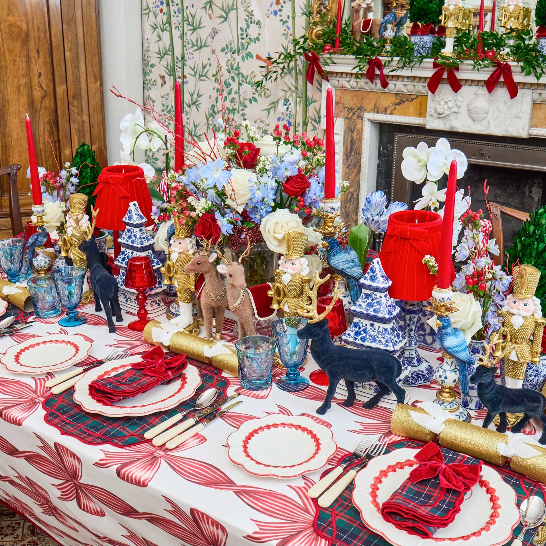 Decorative Christmas table setting with figurines, candles, and a festive tablecloth.