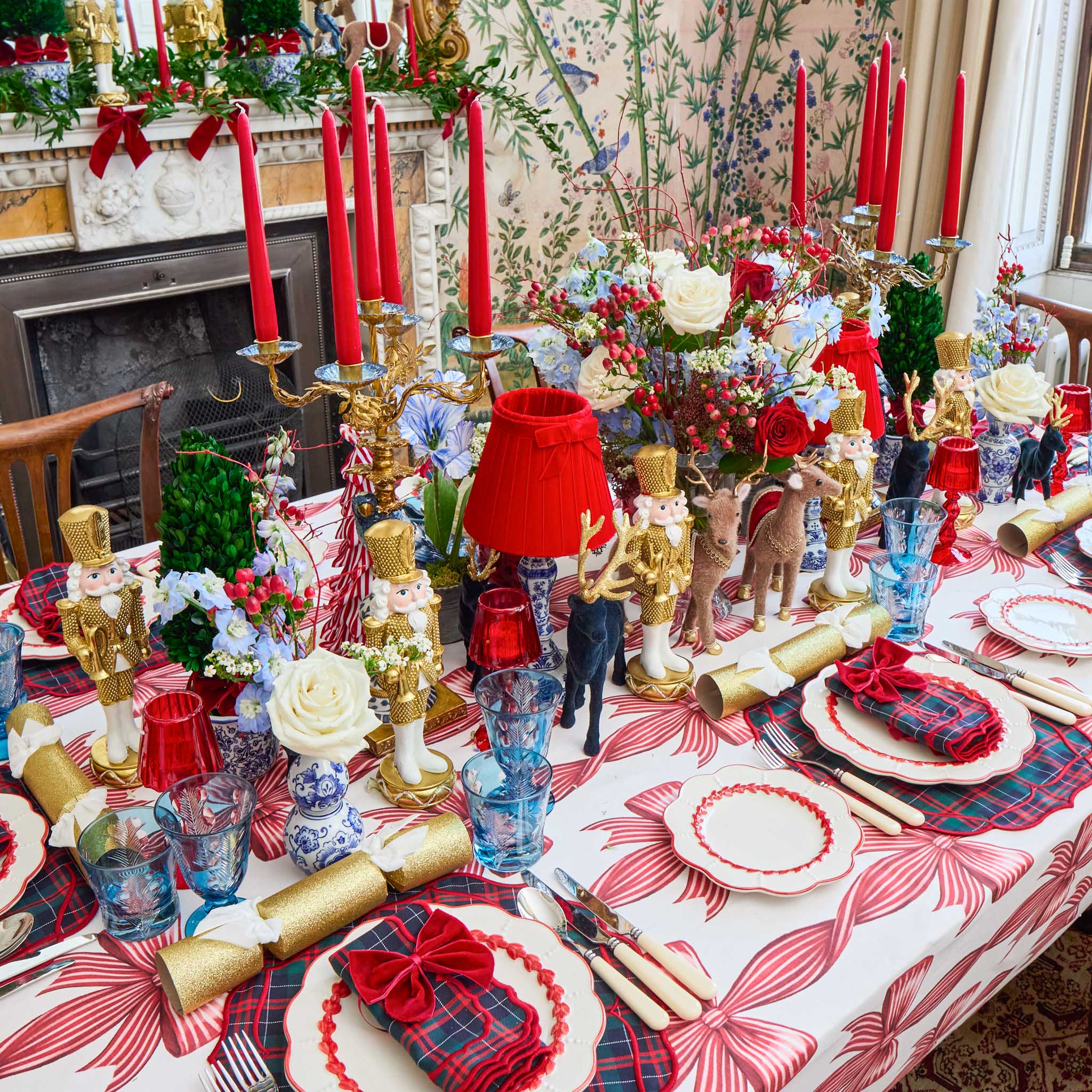 Decorative Christmas table setting with red candles, gold ornaments, and plaid tablecloth.