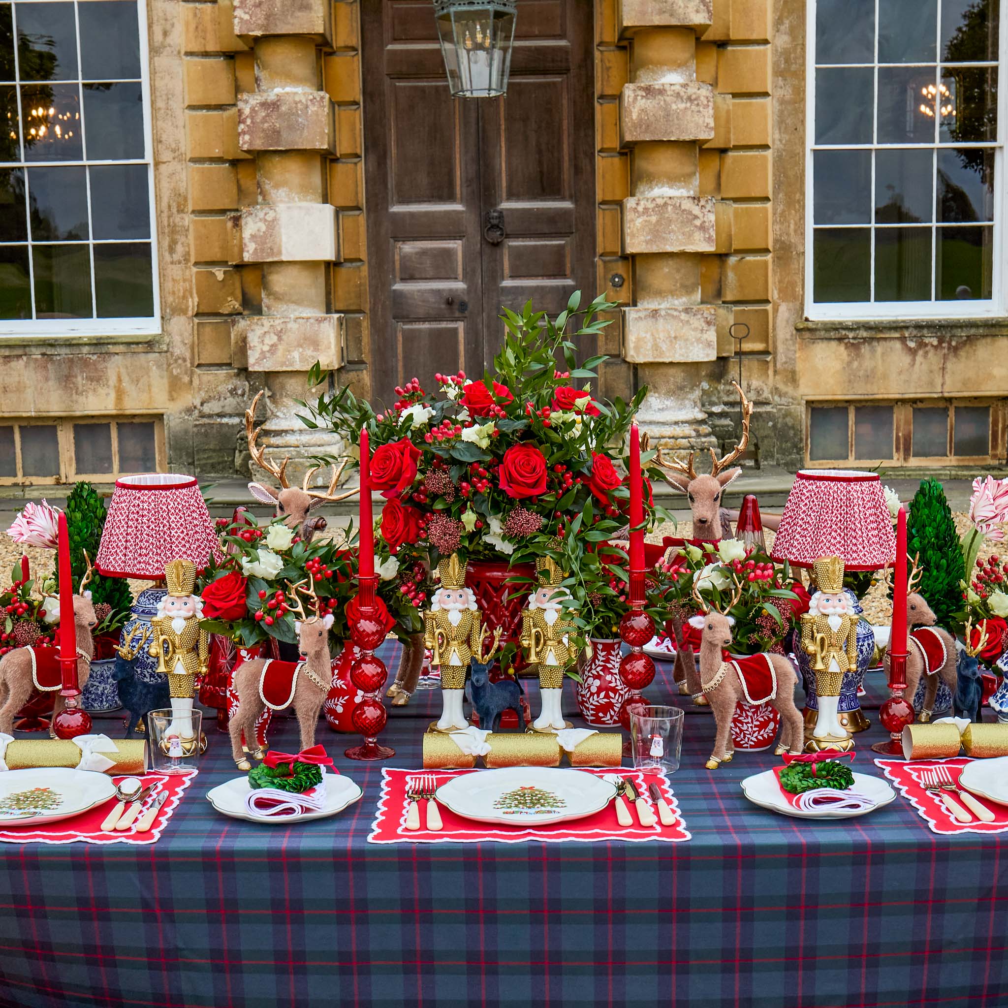 Decorative table setting with red and gold theme in front of a stone building.