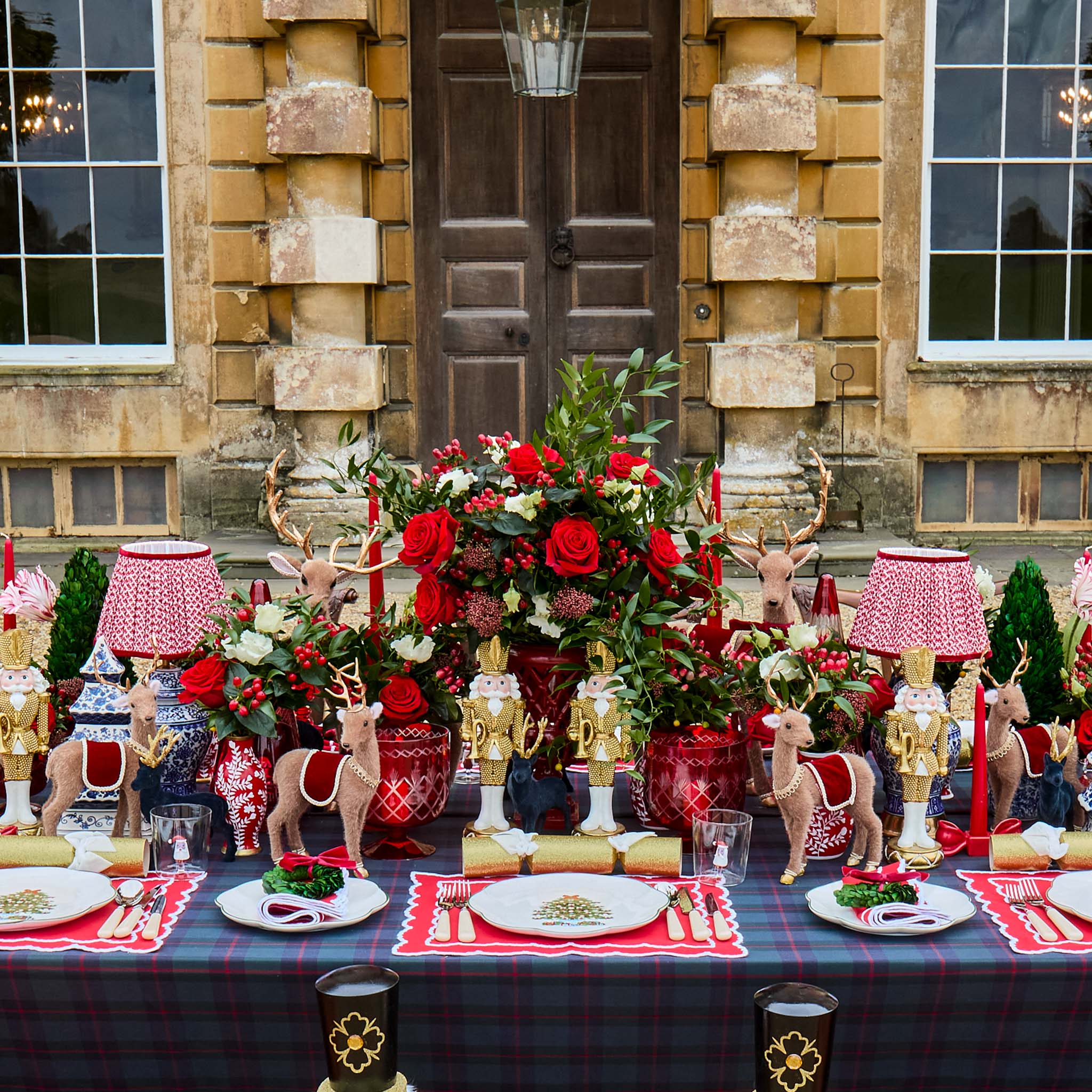 Decorative table setting with red and gold theme in front of a stone building.