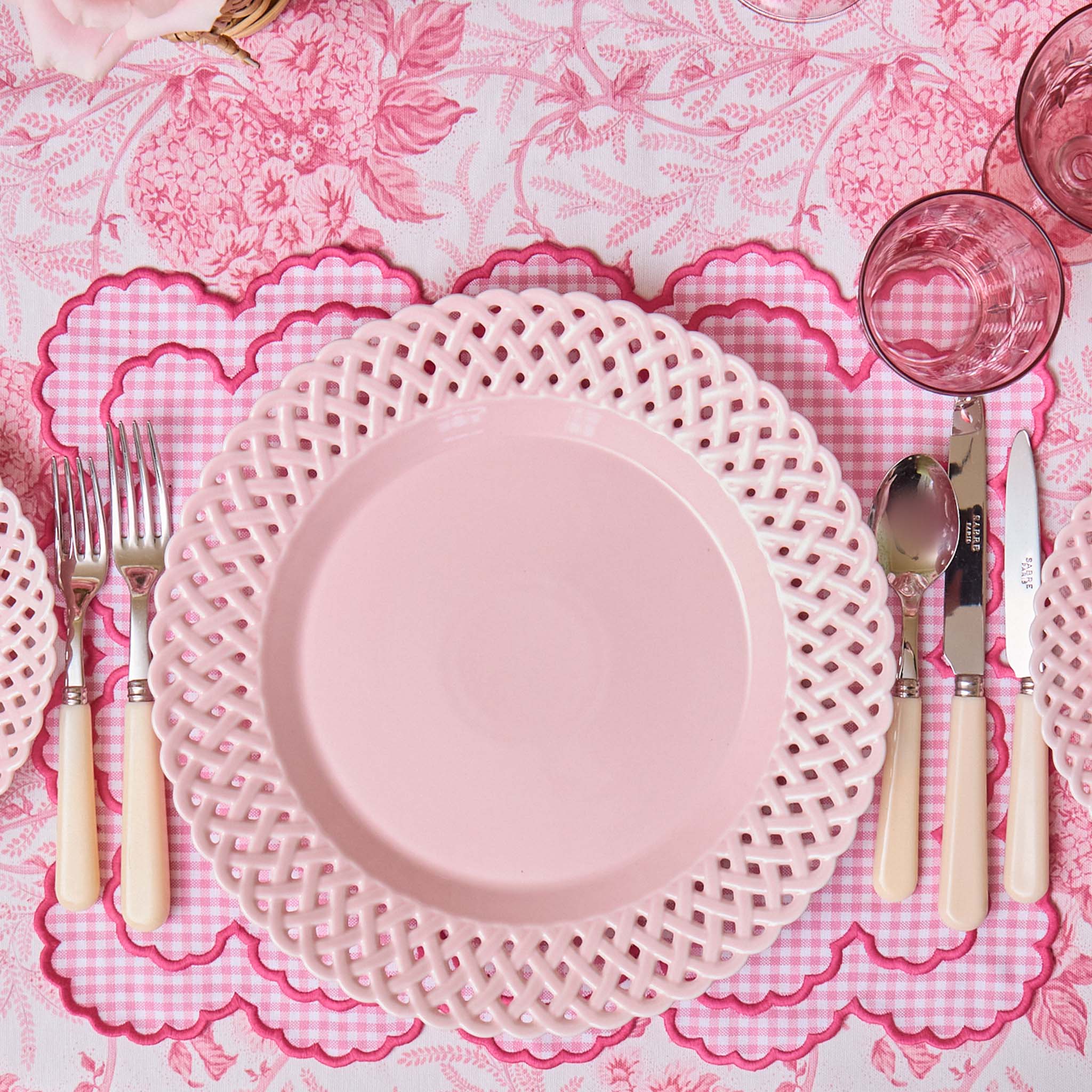 Pink plate with lace rim on a matching pink tablecloth with floral pattern