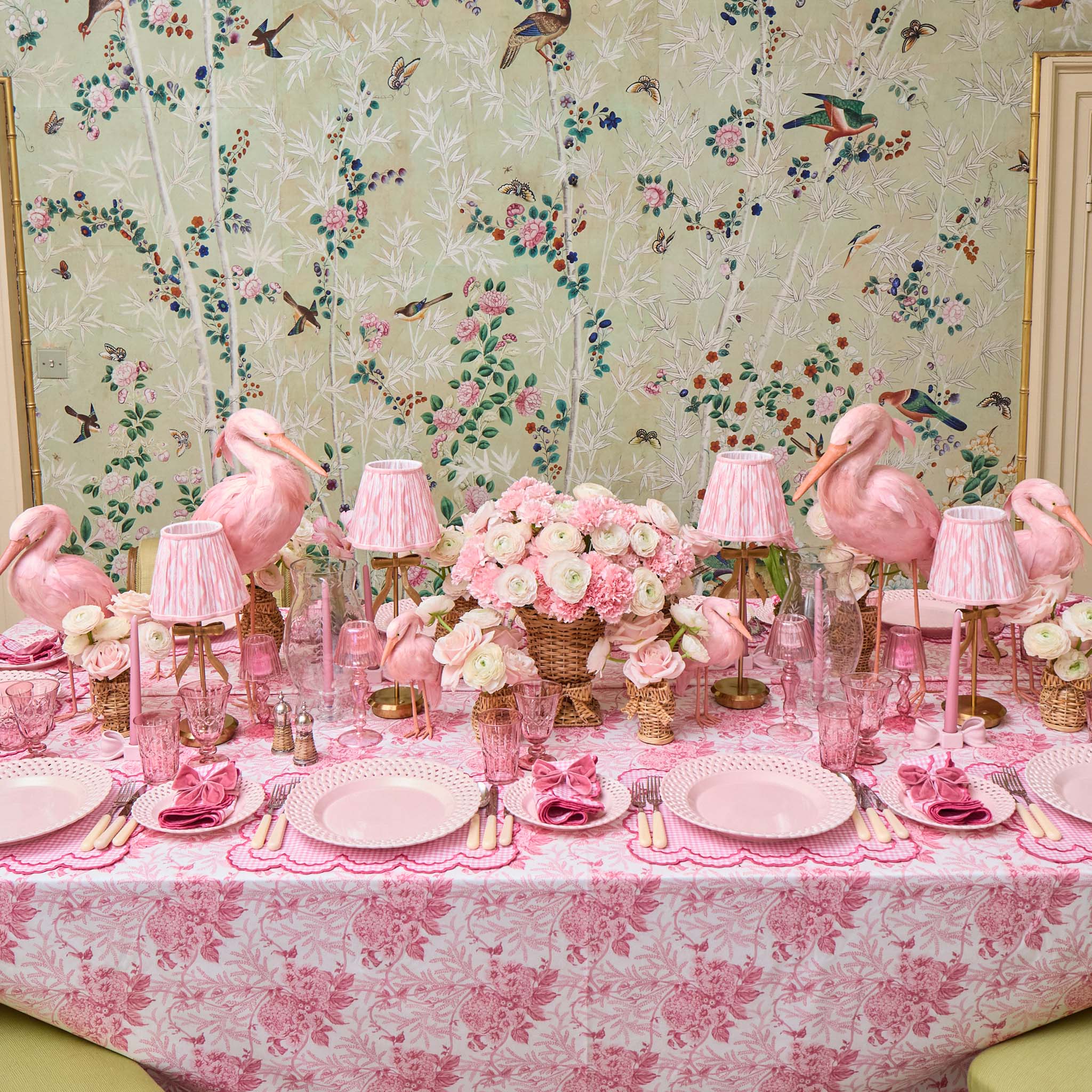 Decorative table setting with pink flamingo decorations against a floral wallpaper background