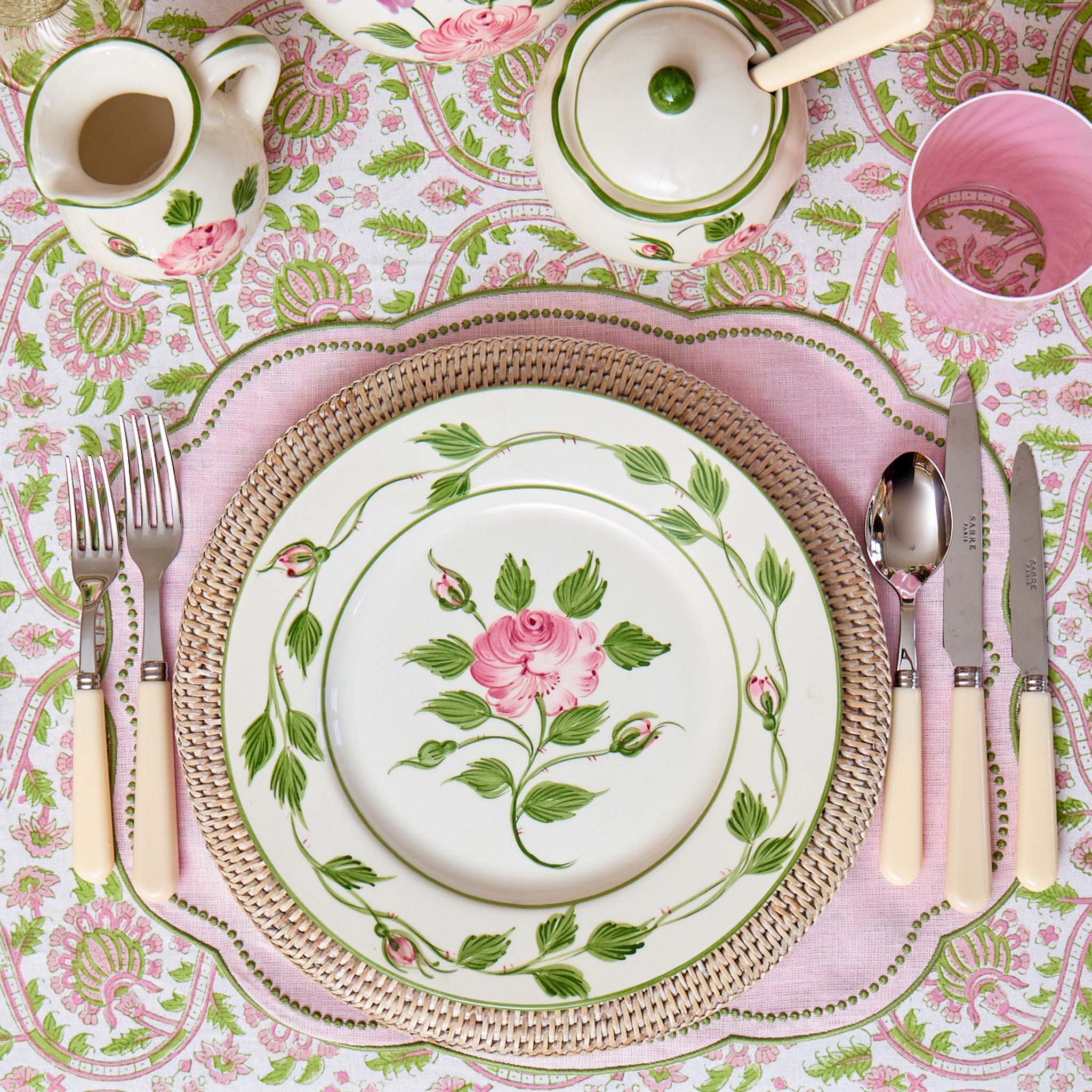 Table setting with floral plates, cutlery, and a patterned tablecloth.