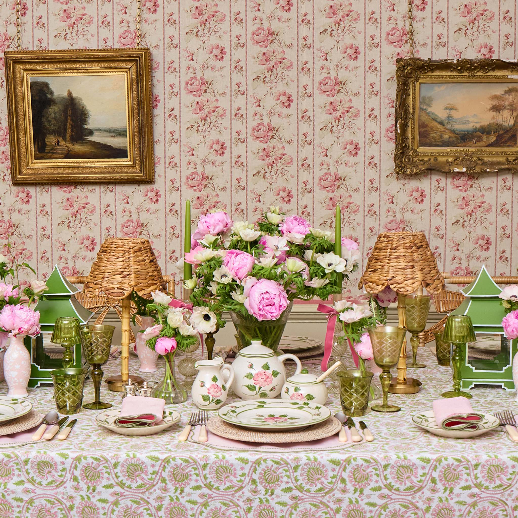 Decorative table setting with floral arrangements and vintage-style decor in a room with floral wallpaper.