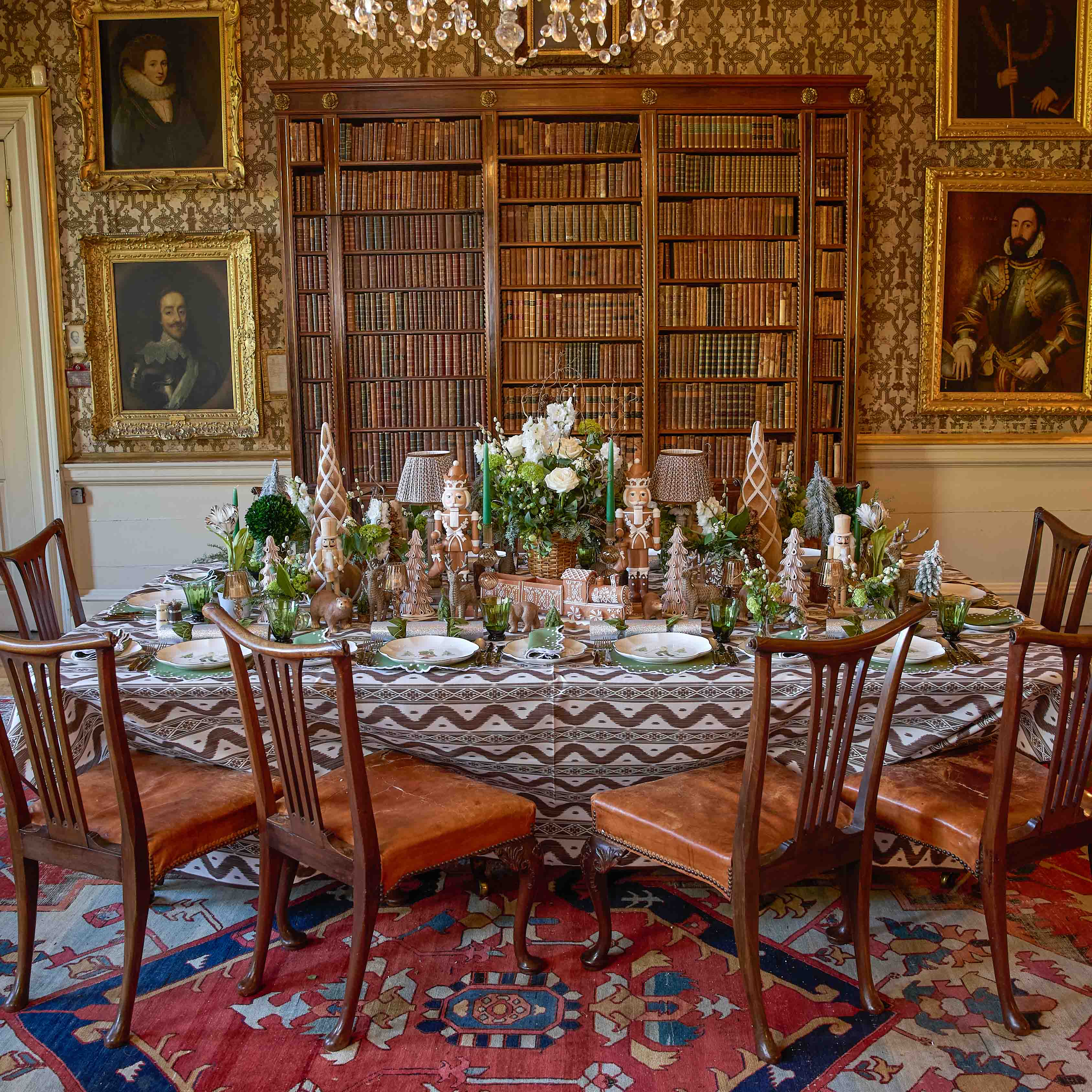 Dining room with ornate table setting, chairs, and bookshelves.
