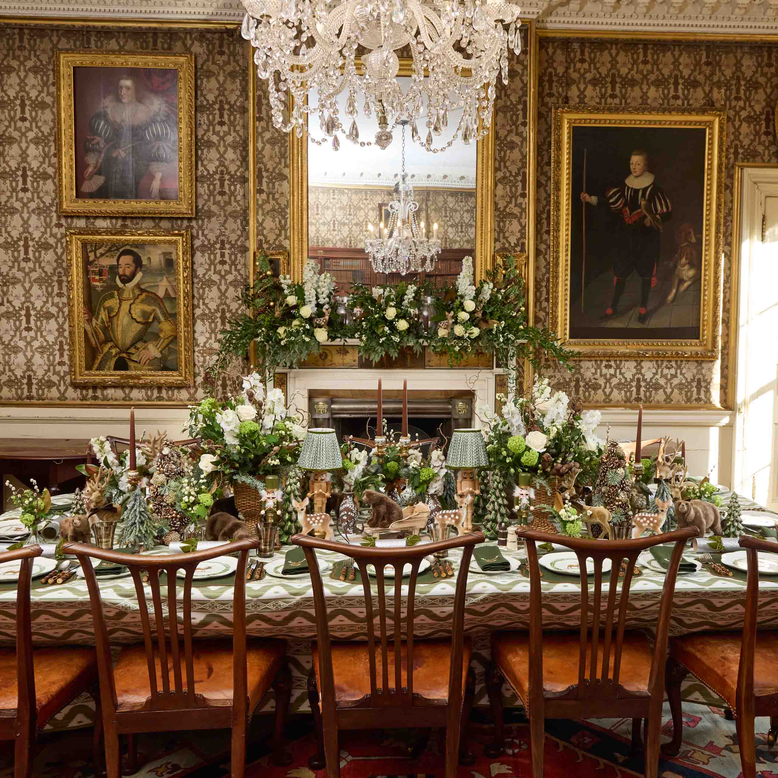 Elegant dining room with ornate decorations, including a chandelier, framed portraits, and a large table set for a formal meal.