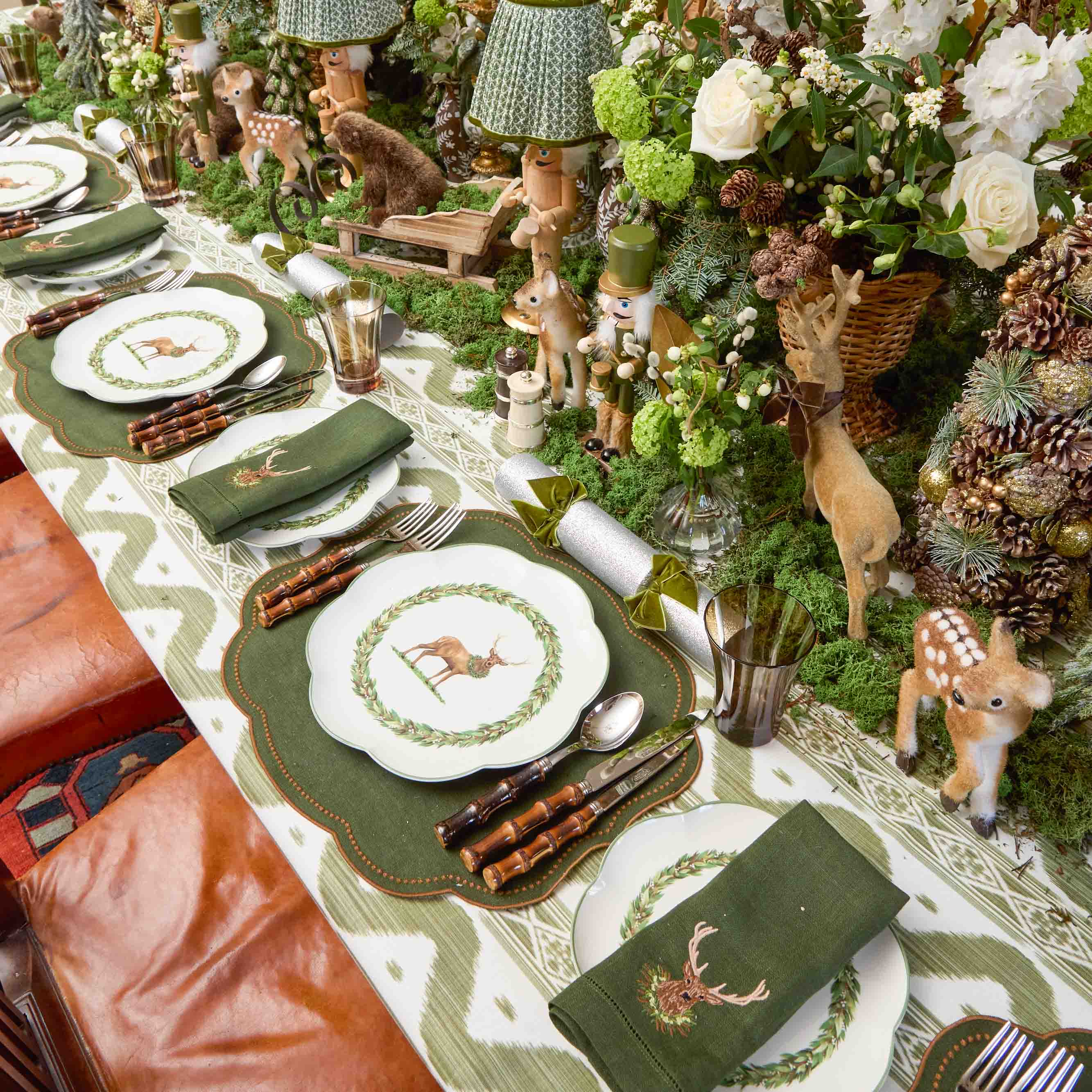 Decorative table setting with deer-themed plates and place mats, surrounded by floral arrangements and wooden decor.