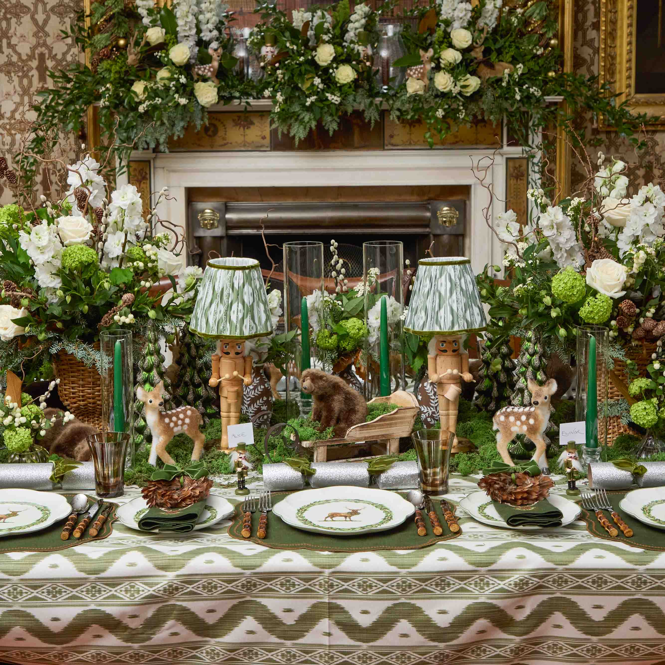 Decorative table setting with floral arrangements, animal figurines, and a fireplace in the background.