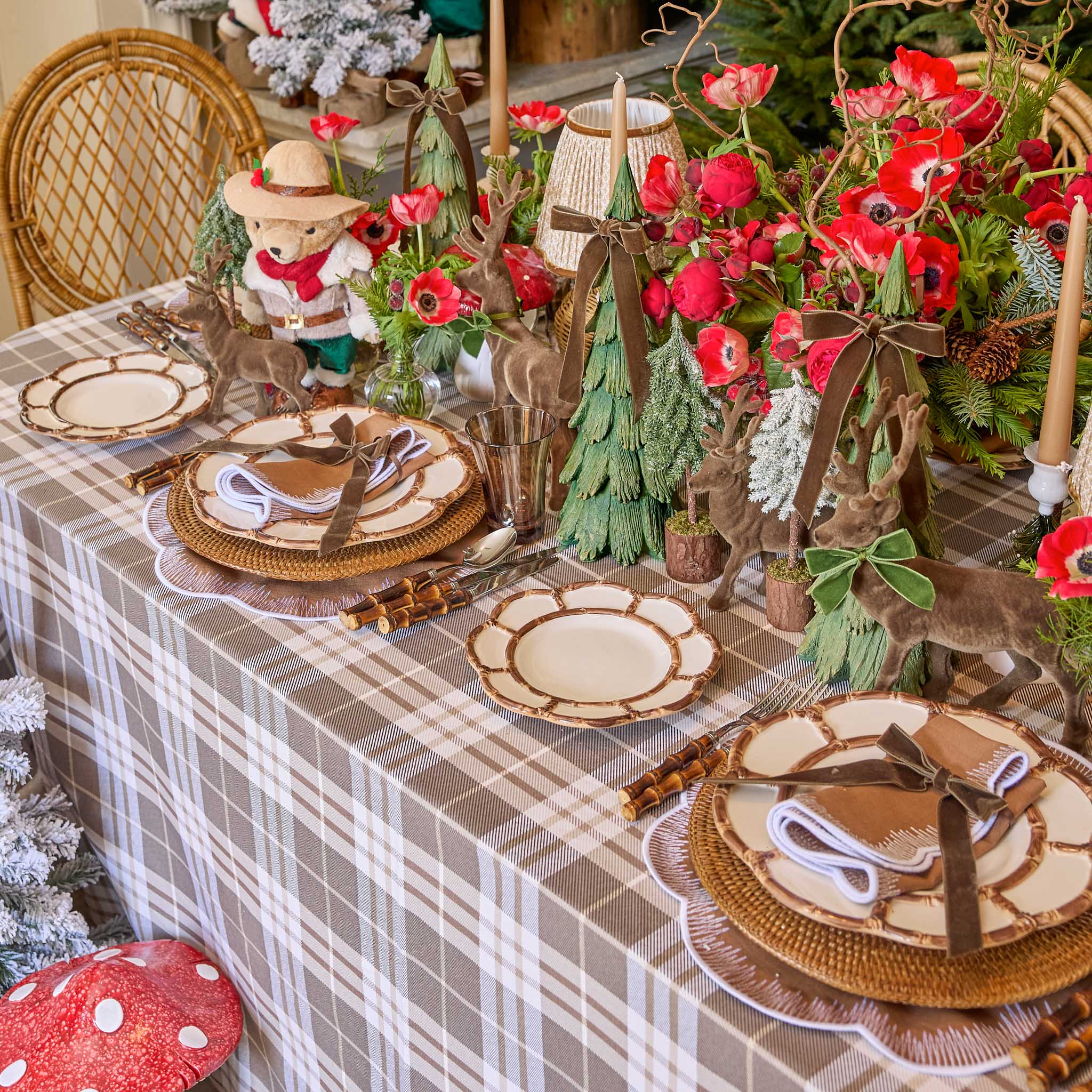 Decorative Christmas table setting with plaid tablecloth, wooden plates, and festive decorations.