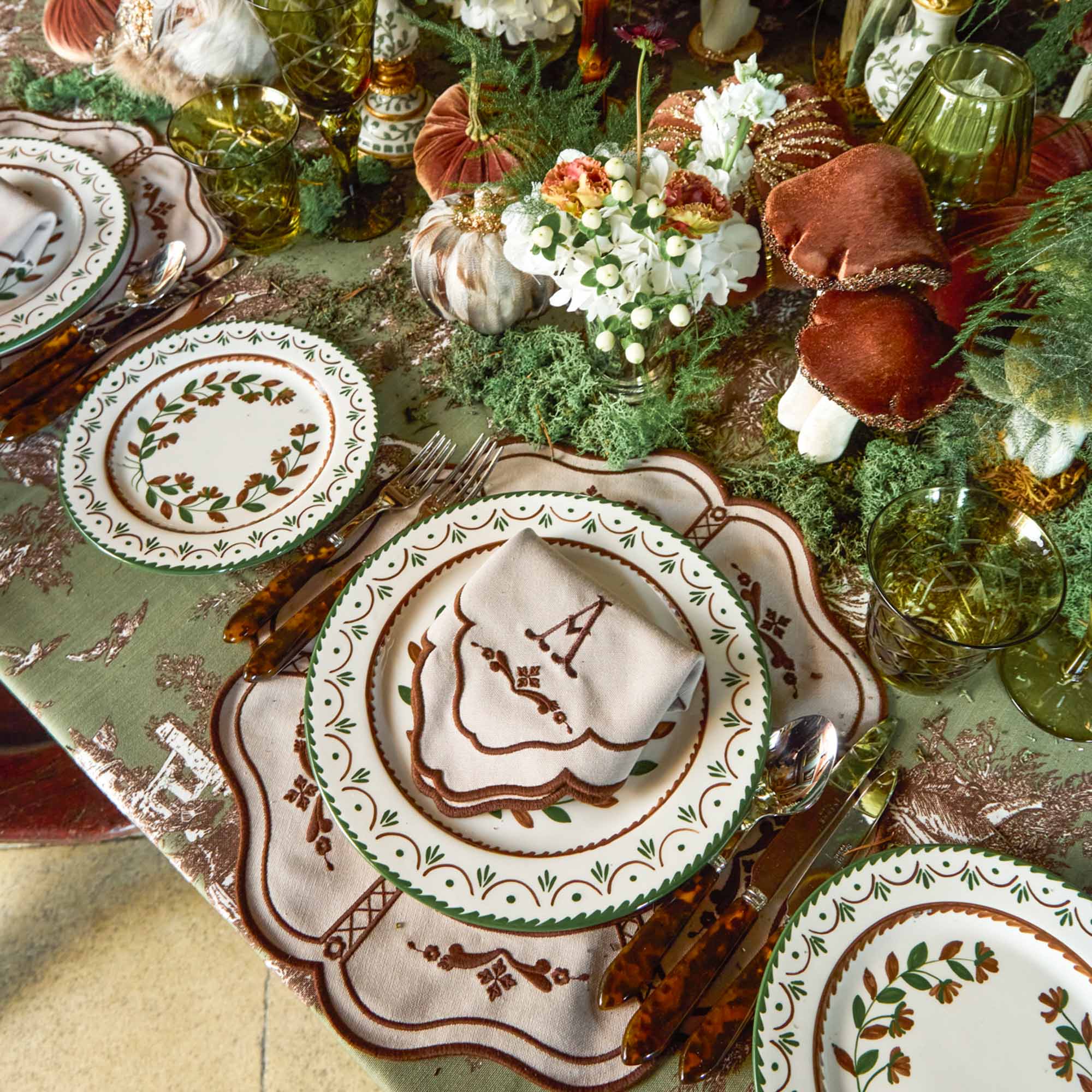 Decorative table setting with patterned plates and cutlery on a textured surface.