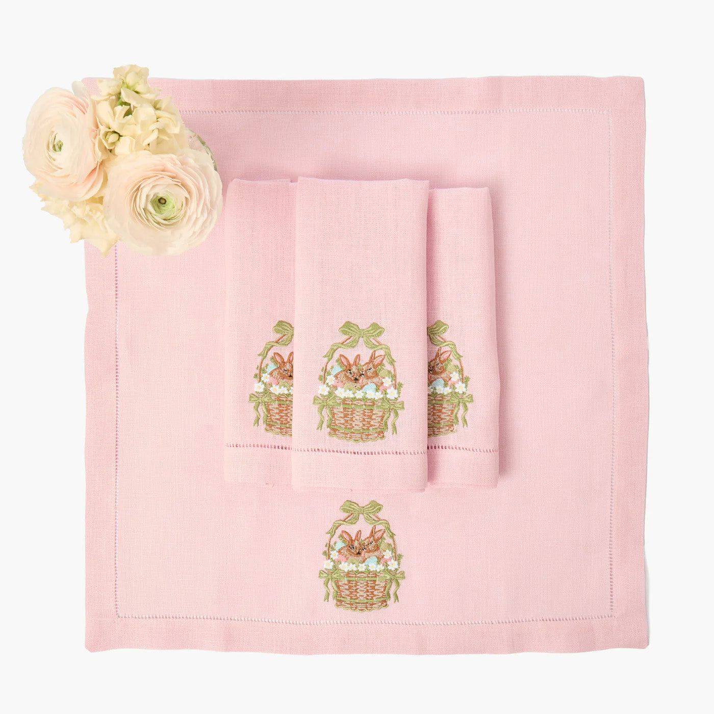 Set of pink towels with embroidered Easter baskets on a white background