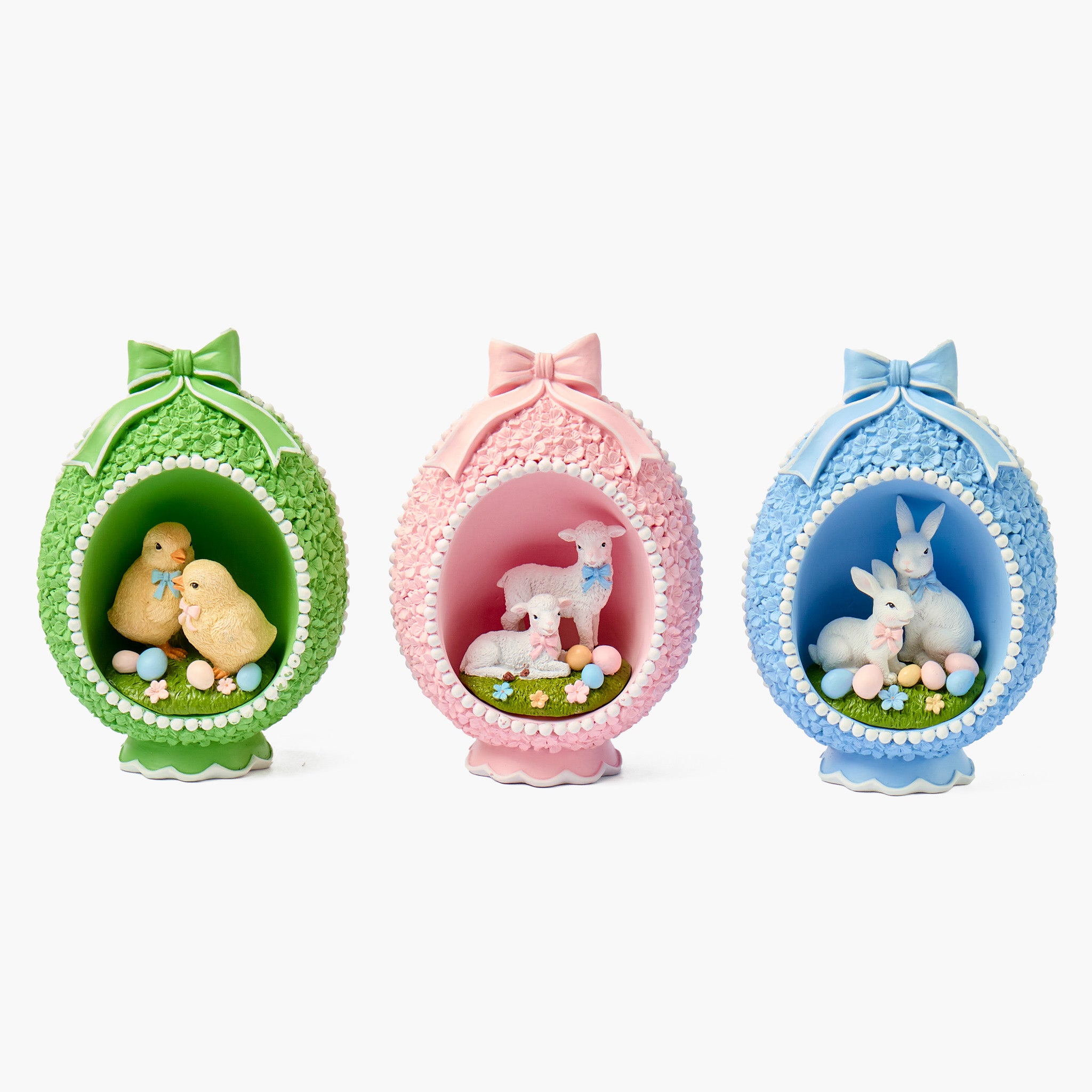 Three decorative Easter egg-shaped figures in green, pink, and blue with small animals inside on a white background.