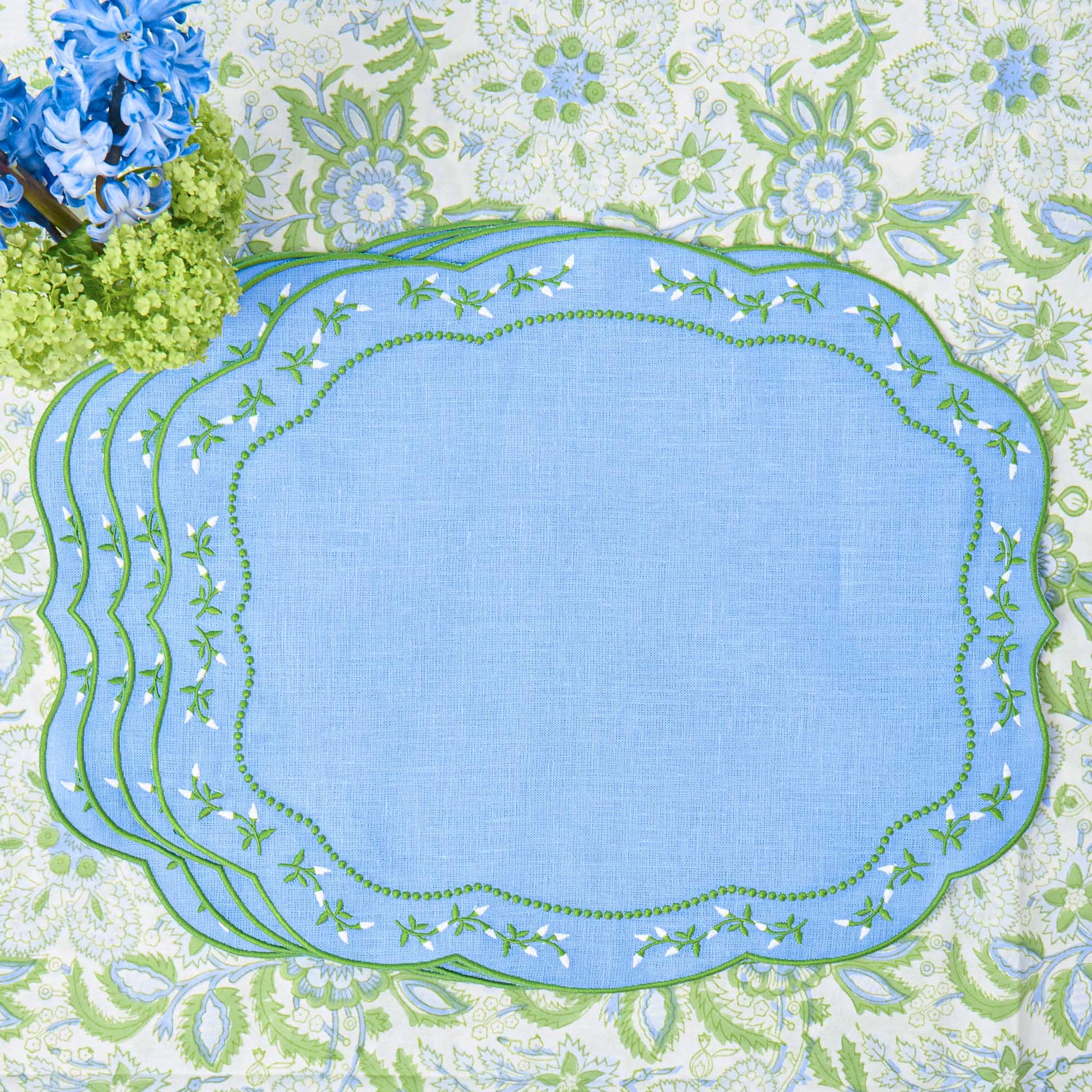 Set of blue placemats with green floral border on a floral background
