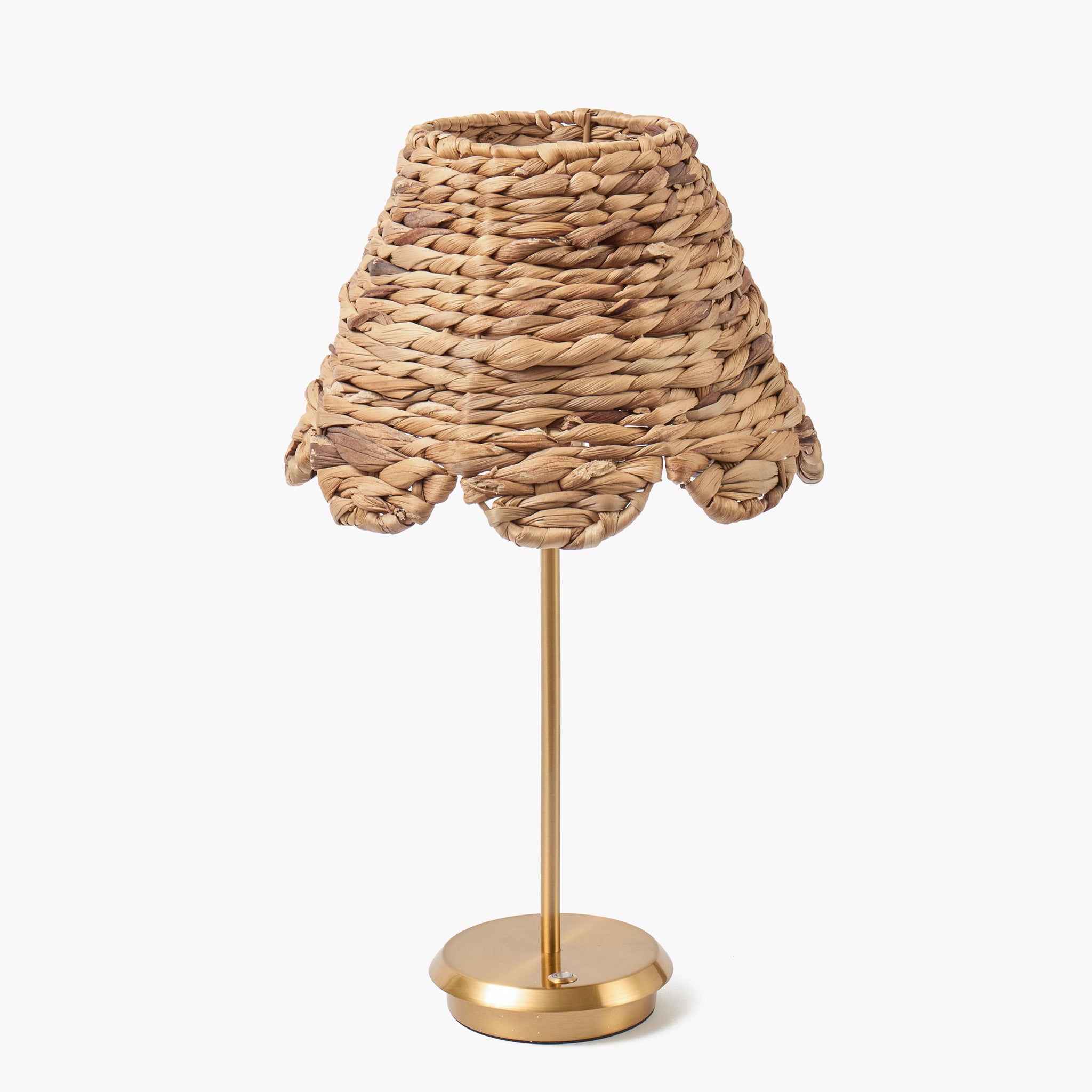 Table lamp with woven shade and gold base on a white background