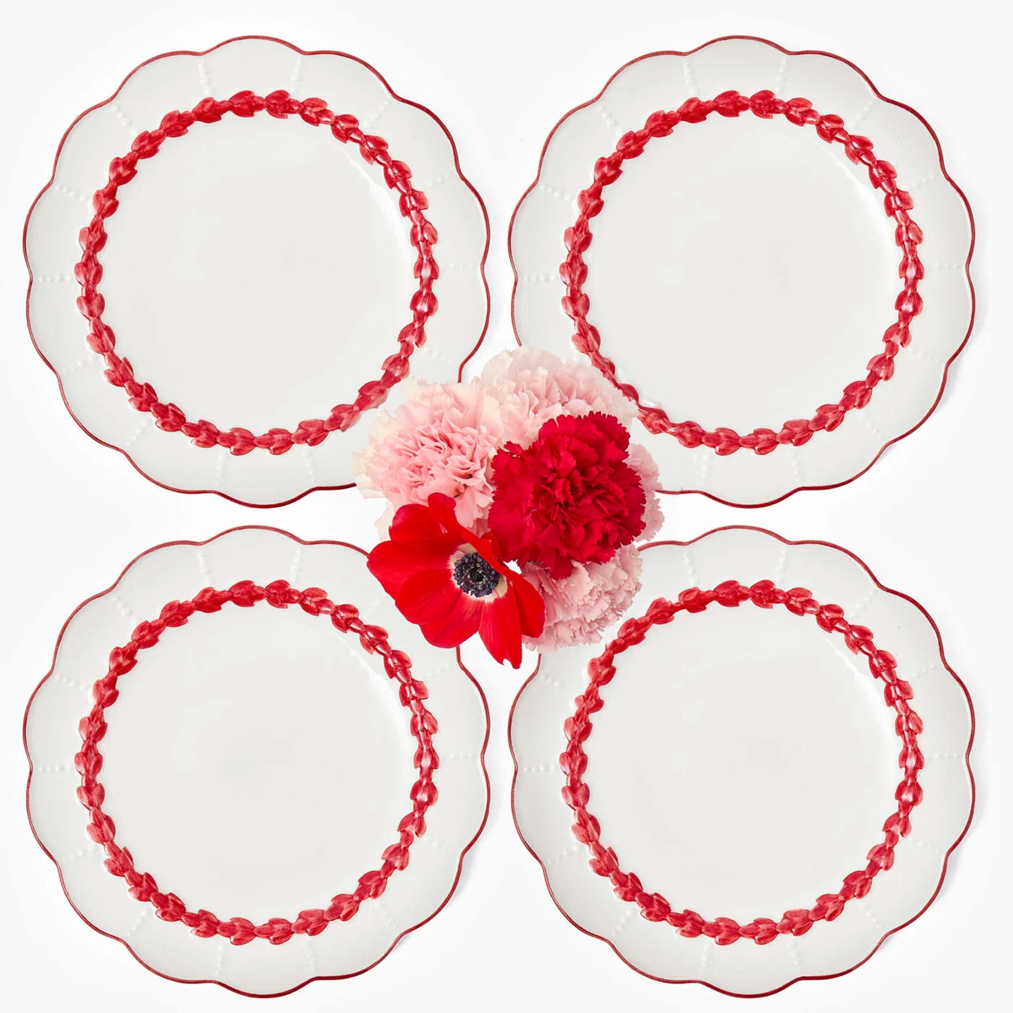 Set of four decorative plates with red floral designs on a white background