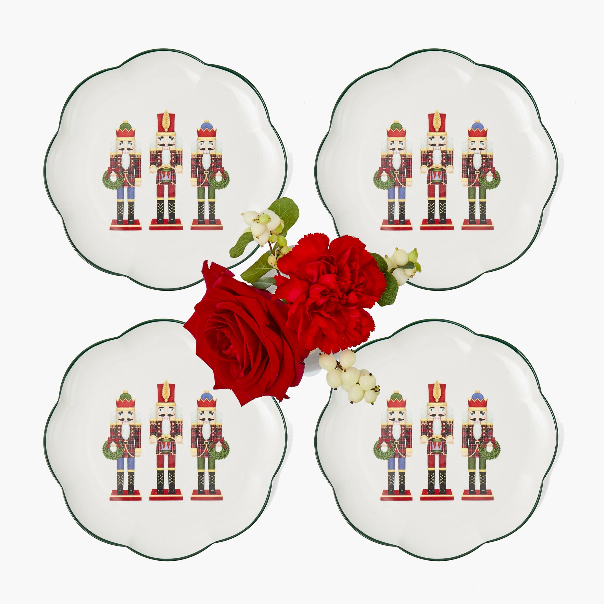 Four decorative plates with nutcracker design and a red rose on a white background