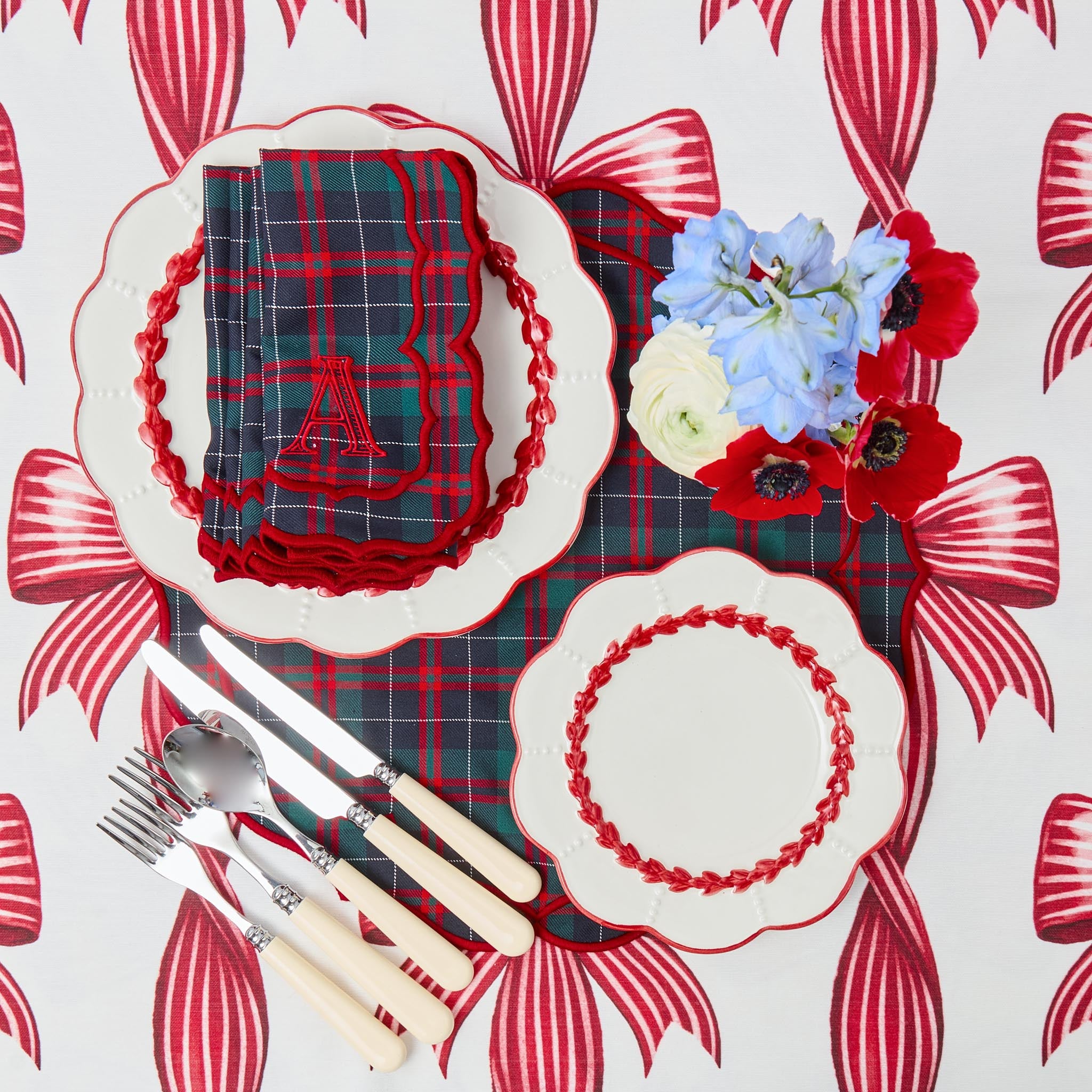 Plaid table setting with red and white floral decorations on a matching tablecloth.
