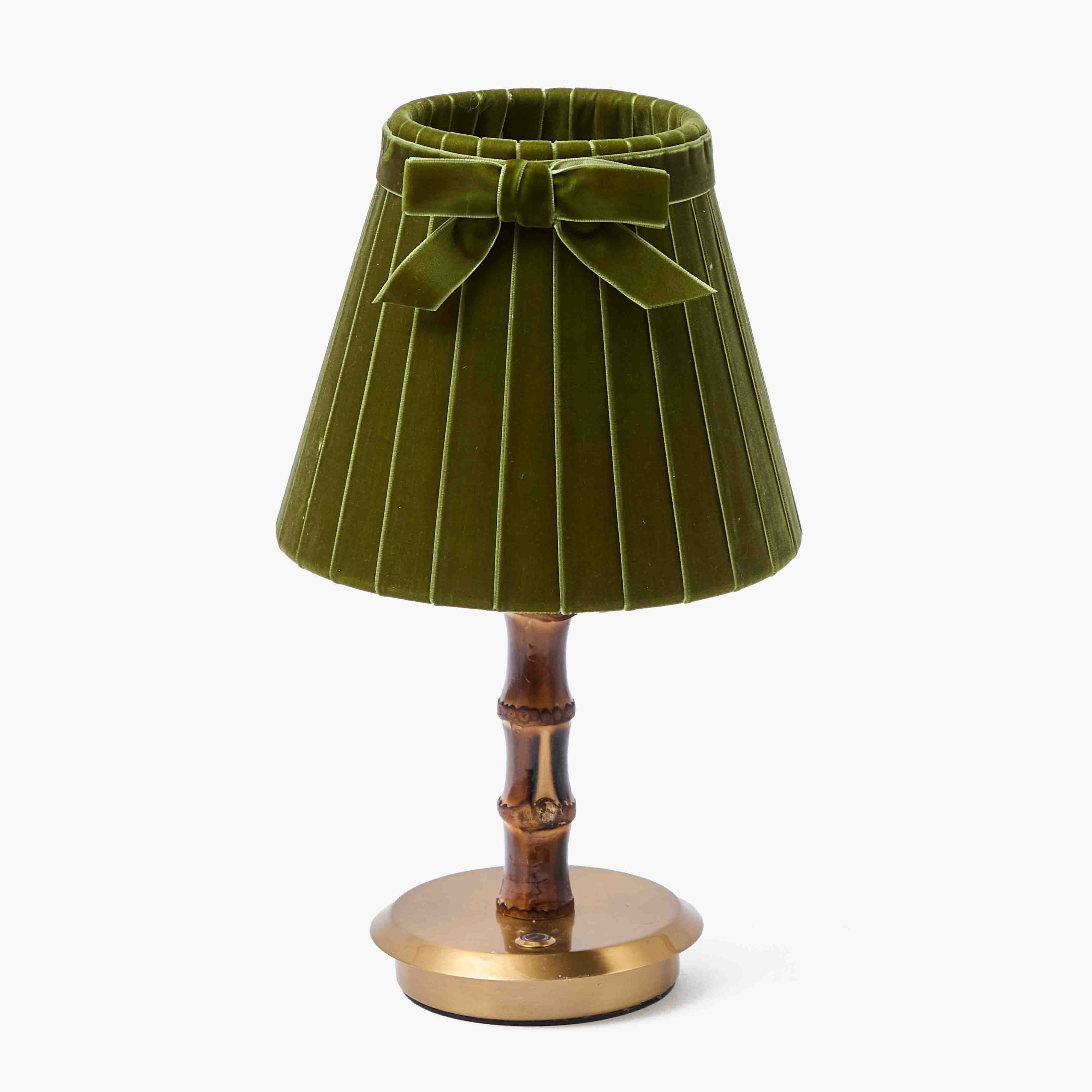 Green pleated lampshade with a bow and wooden base on a white background