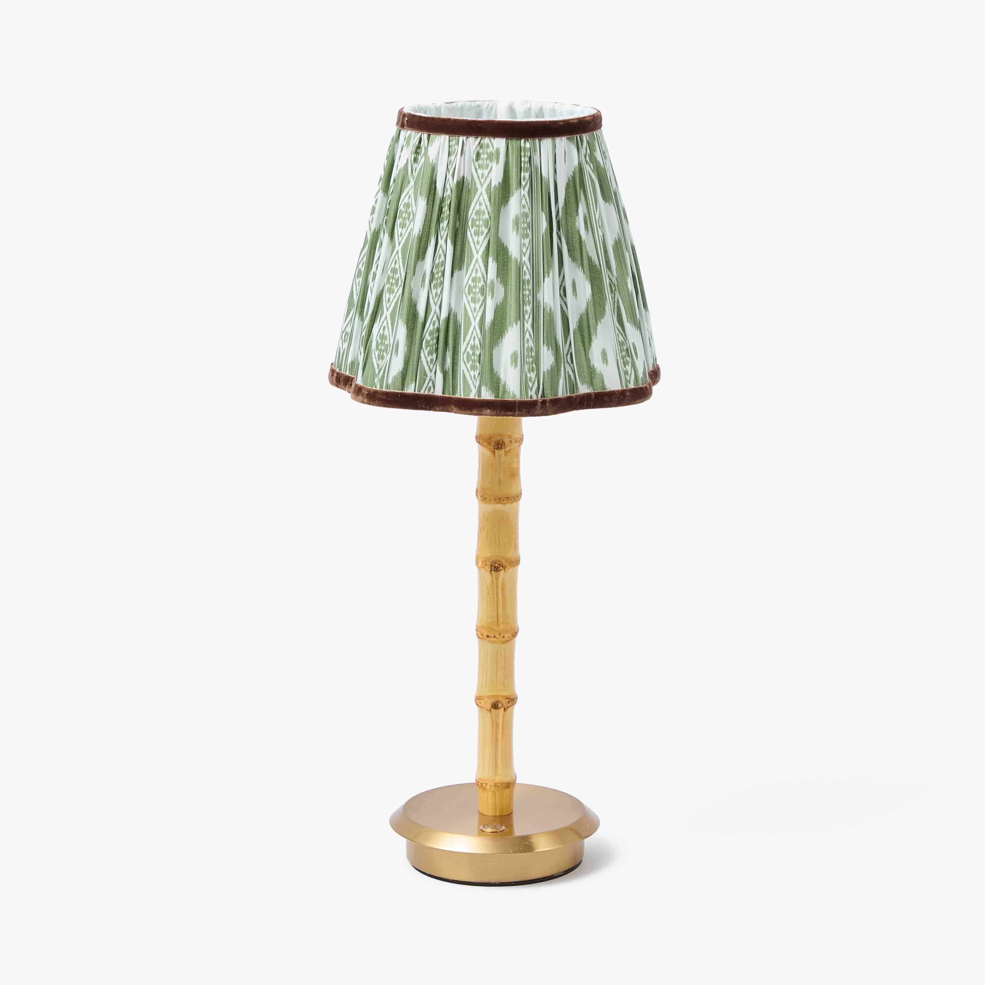 Small lamp with a green ikat patterned shade and gold base on a white background